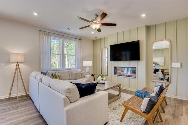 living room featuring recessed lighting, a fireplace, visible vents, baseboards, and light wood-style floors