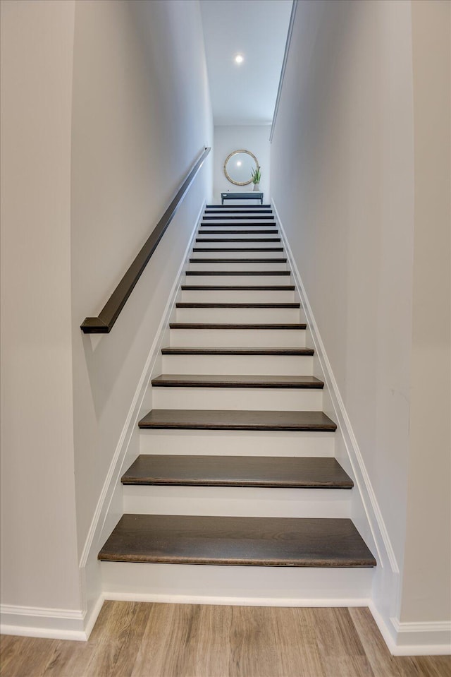 stairway featuring wood finished floors and recessed lighting