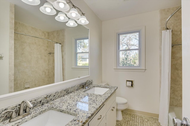 bathroom with double vanity, toilet, baseboards, and a sink