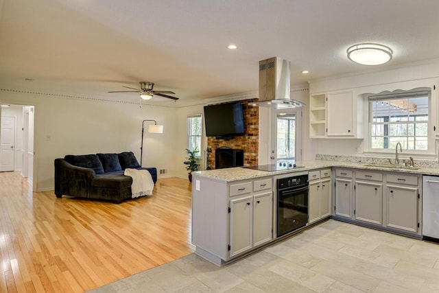 kitchen featuring open shelves, a peninsula, island range hood, black appliances, and a sink