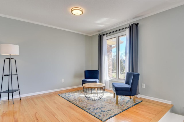 sitting room with wood finished floors, baseboards, and ornamental molding