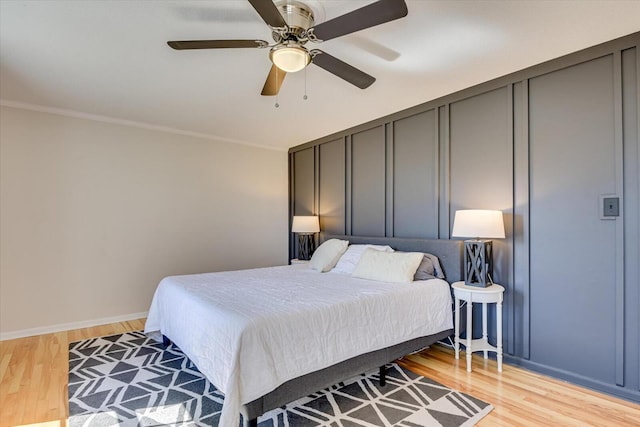 bedroom featuring light wood-style flooring, baseboards, crown molding, and ceiling fan