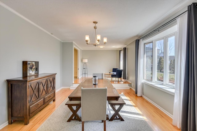 dining area featuring an inviting chandelier, crown molding, light wood-style floors, and baseboards