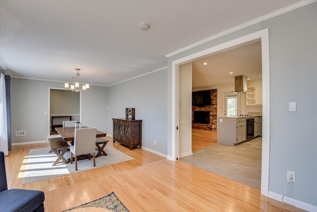 dining space with visible vents, light wood-style floors, an inviting chandelier, and ornamental molding