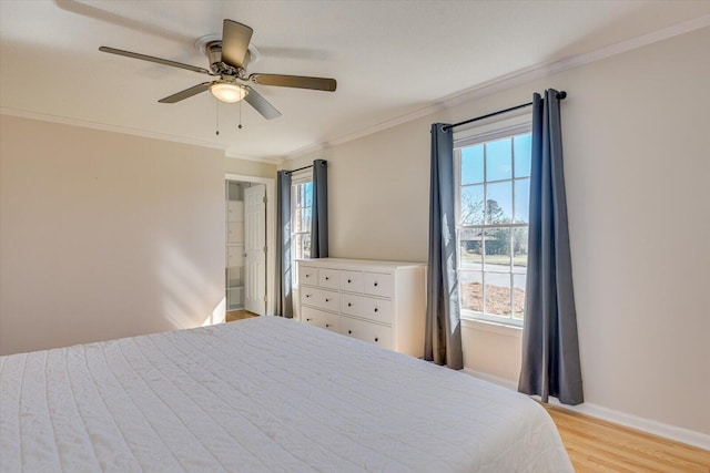 bedroom with multiple windows, baseboards, light wood finished floors, and ornamental molding