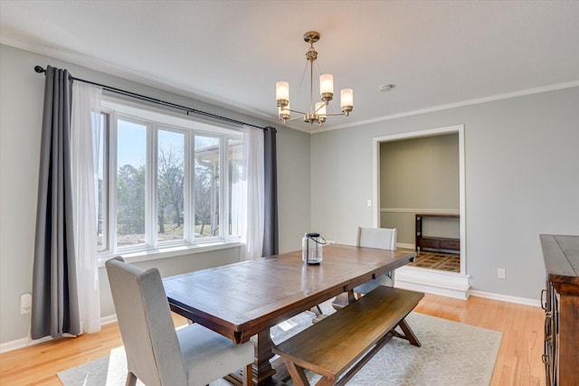 dining area with crown molding, light wood-style flooring, baseboards, and a chandelier