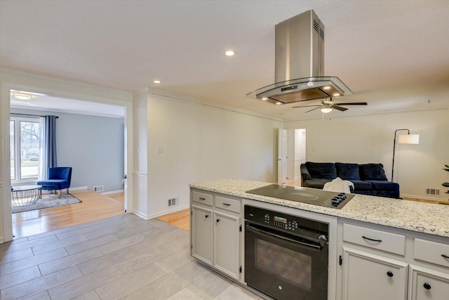 kitchen with visible vents, light wood-type flooring, black appliances, a ceiling fan, and island exhaust hood