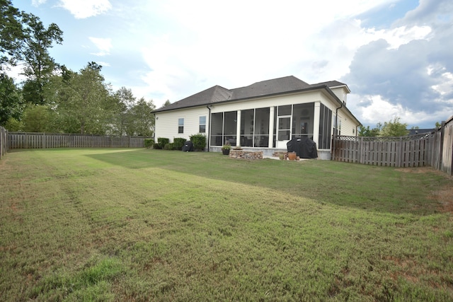 rear view of property featuring a sunroom and a lawn