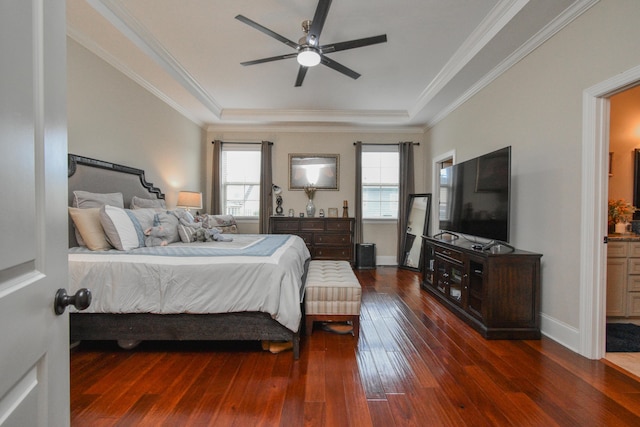 bedroom with a raised ceiling, crown molding, ceiling fan, connected bathroom, and dark hardwood / wood-style flooring