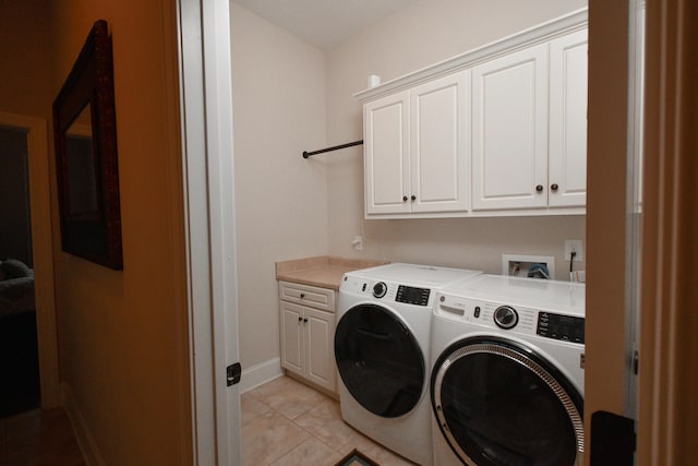 clothes washing area with washer and clothes dryer, cabinets, and light tile patterned floors