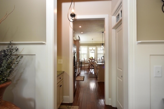 corridor with crown molding, dark wood-type flooring, and sink