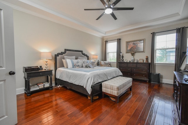 bedroom featuring ceiling fan, ornamental molding, dark wood-type flooring, and a tray ceiling