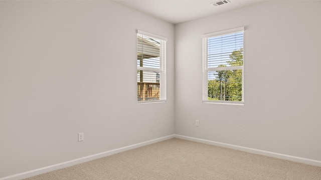 spare room with visible vents, light colored carpet, and baseboards