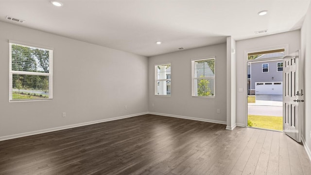 spare room with dark wood finished floors, recessed lighting, a healthy amount of sunlight, and visible vents