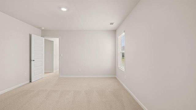 unfurnished room featuring visible vents, baseboards, and light carpet