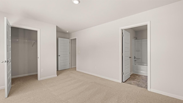 unfurnished bedroom featuring a closet, baseboards, ensuite bath, and carpet flooring