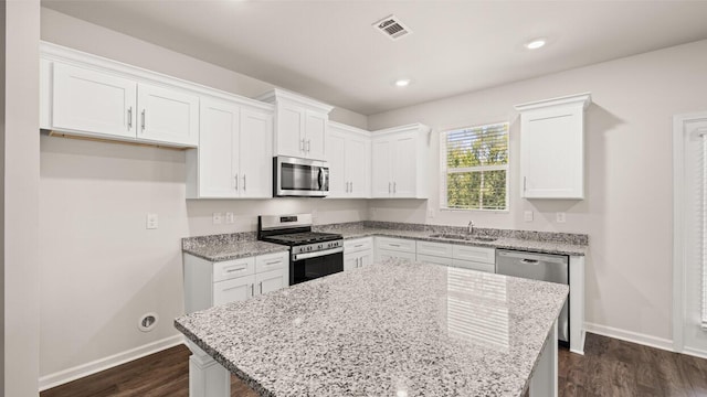 kitchen with light stone counters, dark wood-style floors, visible vents, appliances with stainless steel finishes, and white cabinetry