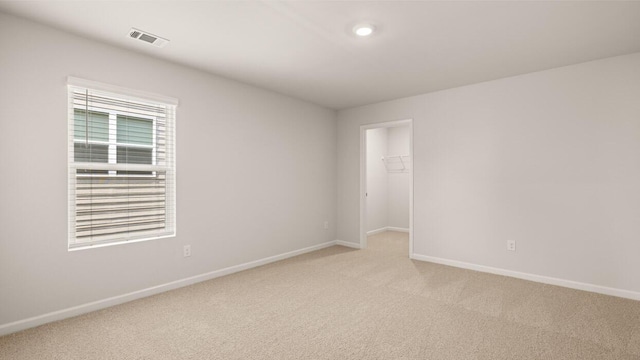 spare room featuring visible vents, light colored carpet, and baseboards