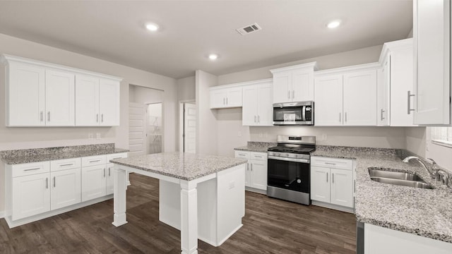 kitchen featuring dark wood-style floors, visible vents, a sink, stainless steel appliances, and white cabinetry