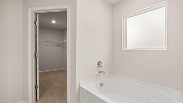 full bathroom featuring a garden tub and a spacious closet