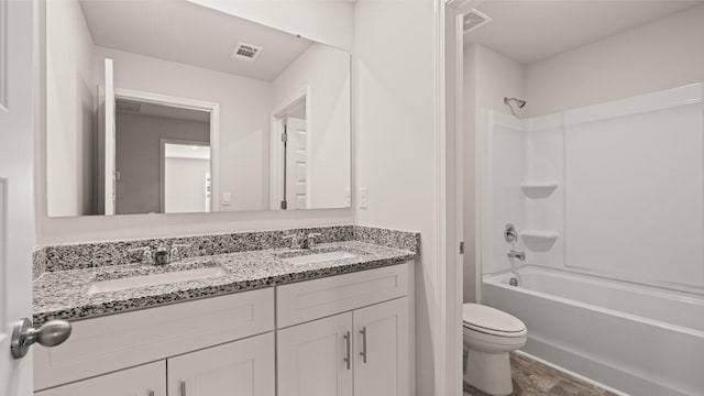 bathroom with double vanity, visible vents, toilet, and a sink