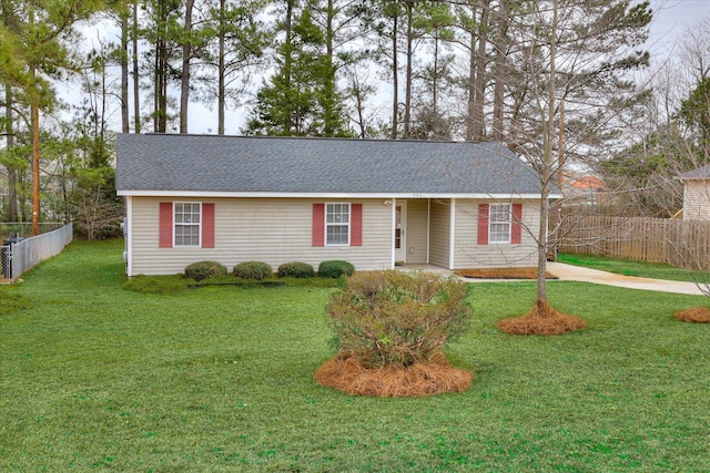 ranch-style house with a shingled roof, fence, and a front lawn