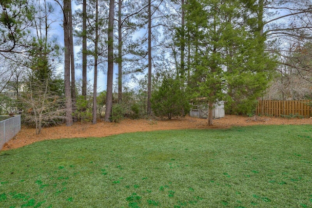view of yard featuring a storage shed, fence, and an outdoor structure