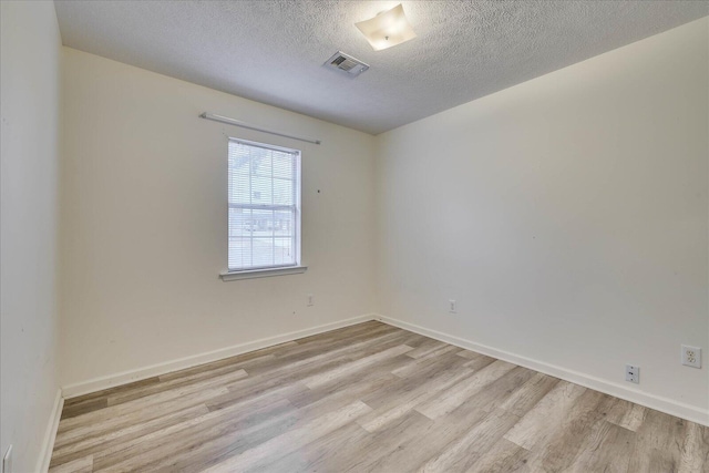 empty room featuring light wood-style floors, baseboards, and visible vents
