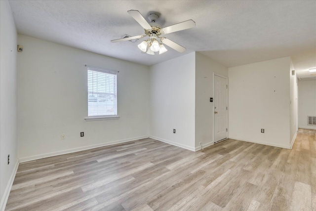 empty room featuring light wood-style floors, ceiling fan, visible vents, and a textured ceiling