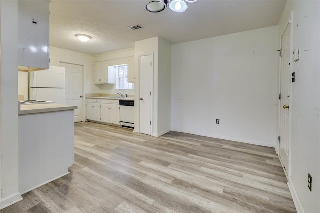 kitchen with white appliances, visible vents, light wood-style flooring, light countertops, and a textured ceiling