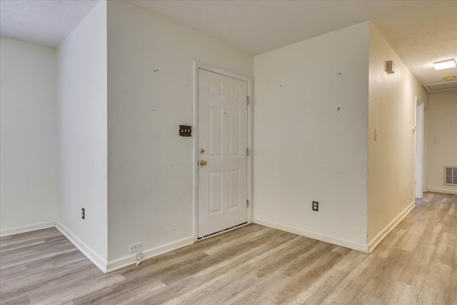 spare room featuring light wood-style flooring, visible vents, and baseboards