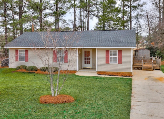 ranch-style house with a front lawn, roof with shingles, and a wooden deck