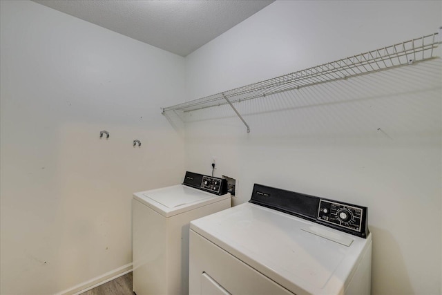 laundry room with laundry area, baseboards, washer and clothes dryer, wood finished floors, and a textured ceiling