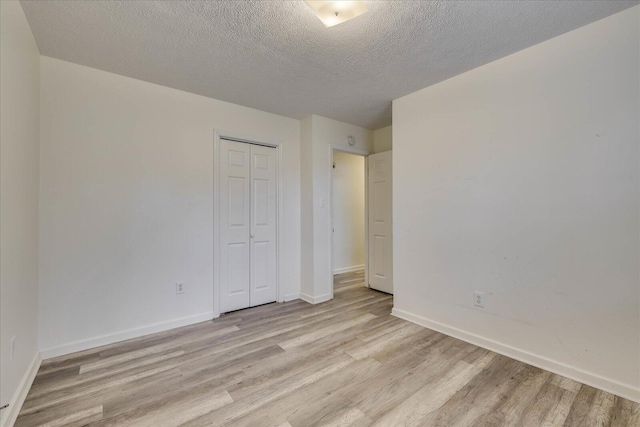 unfurnished bedroom featuring baseboards, a closet, and light wood-style floors