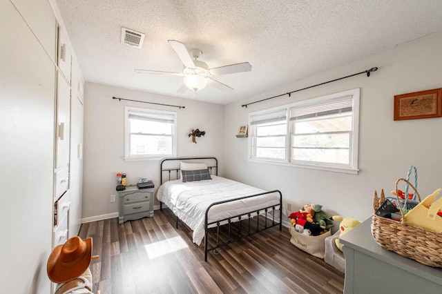bedroom featuring a ceiling fan, a textured ceiling, baseboards, dark wood-type flooring, and visible vents
