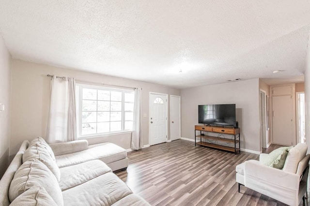 living room featuring visible vents, baseboards, wood finished floors, and a textured ceiling