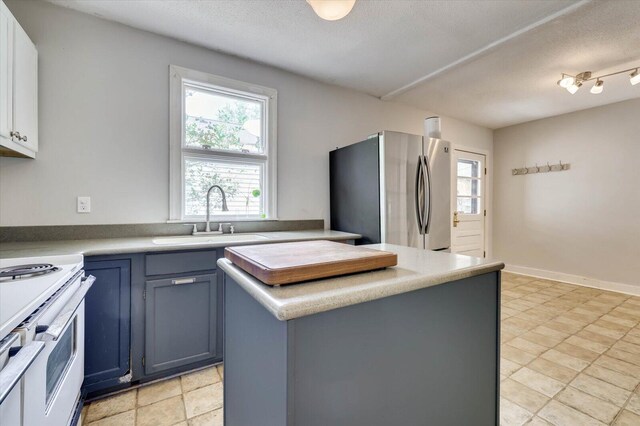 kitchen featuring stainless steel fridge, a textured ceiling, sink, white electric range, and a kitchen island