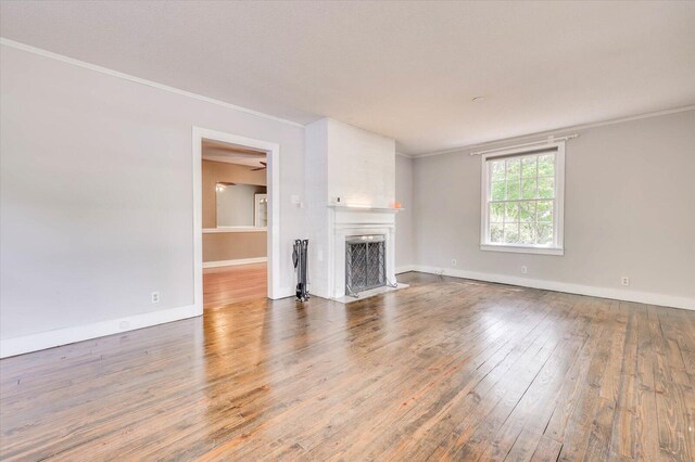 unfurnished living room with crown molding, a fireplace, and hardwood / wood-style flooring