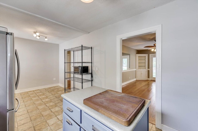 kitchen with a textured ceiling, stainless steel refrigerator, and ceiling fan