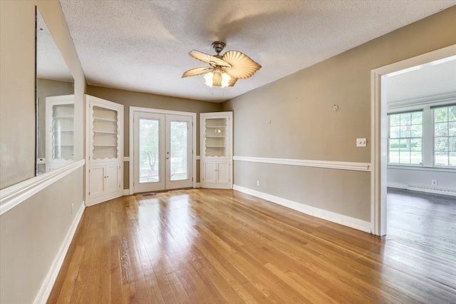 unfurnished room featuring ceiling fan, light hardwood / wood-style flooring, a textured ceiling, and french doors