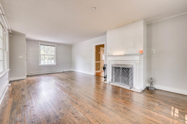 unfurnished living room with hardwood / wood-style flooring, crown molding, and a baseboard heating unit