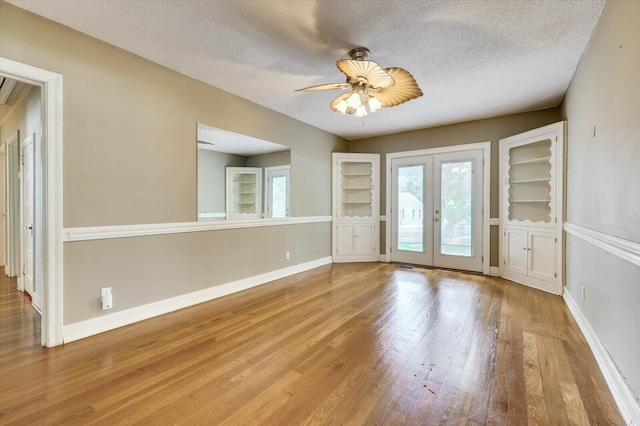 unfurnished room with ceiling fan, french doors, a textured ceiling, and light hardwood / wood-style flooring