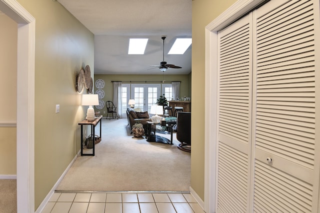 hallway with a skylight, light colored carpet, and french doors