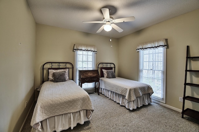 carpeted bedroom featuring baseboards, a textured ceiling, and a ceiling fan