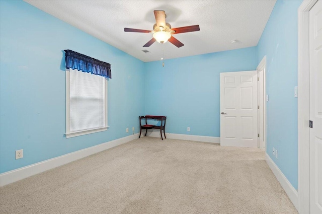 empty room featuring a textured ceiling, ceiling fan, and light carpet