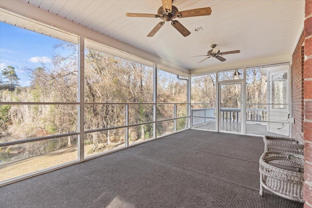 unfurnished sunroom featuring ceiling fan and a wealth of natural light