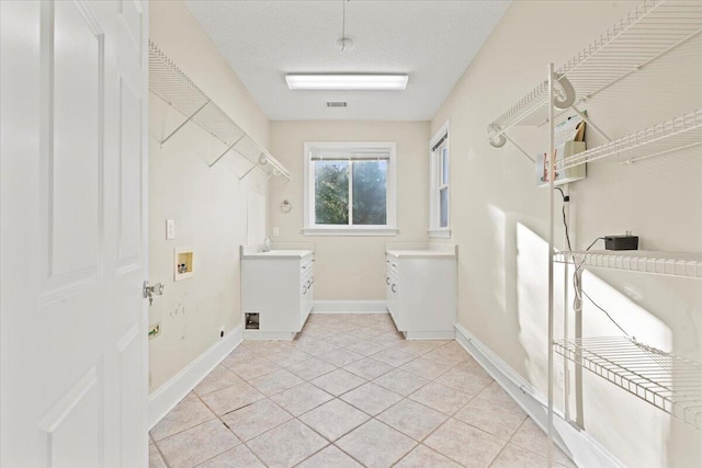 washroom with washer hookup, a textured ceiling, and light tile patterned flooring