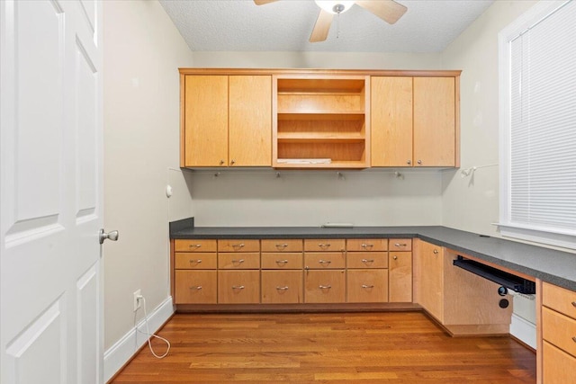 unfurnished office with ceiling fan, a textured ceiling, and hardwood / wood-style flooring