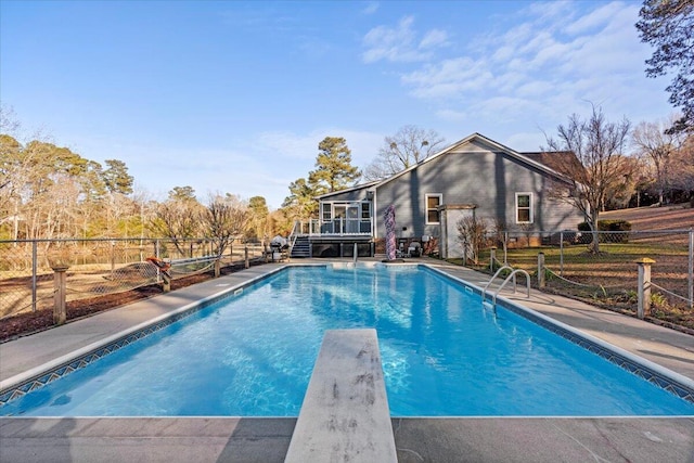 view of pool with a diving board and a deck