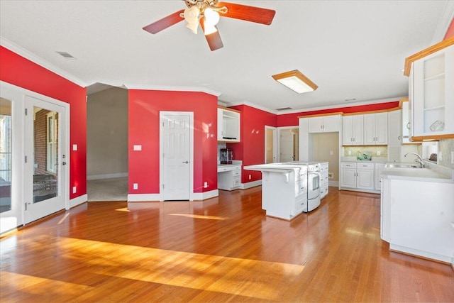 kitchen with a center island, white cabinets, crown molding, decorative backsplash, and a kitchen bar